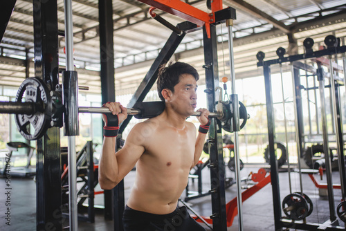 Man doing squat exercises with a barbell in gym