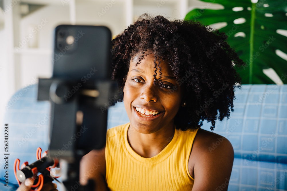 © ADDICTIVE STOCK - Happy black woman with microphone in living room