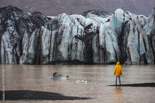 Fotografie Girl in yellow raincoast against the backdrop of a powerful vast high glacier Mý
