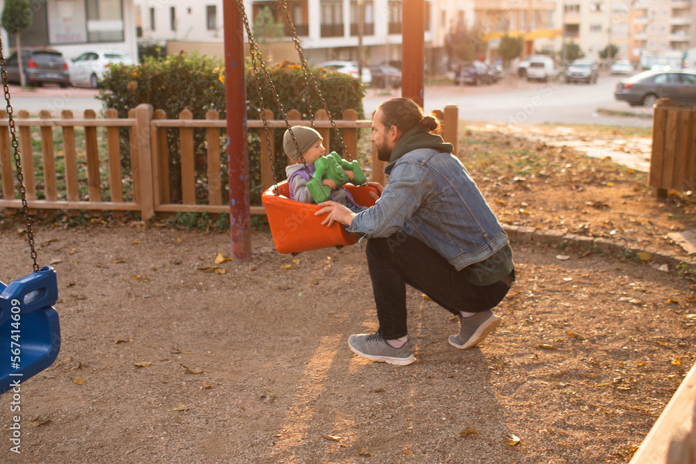Dad and child are playing on the playground. Swing and slide rides. Dad and child are playing on the playground. Swing and slide rides.