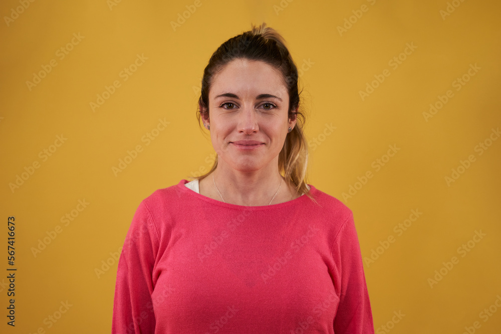 Isolated portrait of a blonde caucasian woman looking at camera smiling, while standing against a yellow background. Copy space. Isolated portrait of a blonde caucasian woman looking at camera smiling, while standing against a yellow background. Copy space.