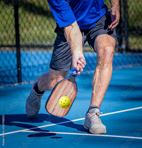 Pickleball player his a low volley using a forehand shot