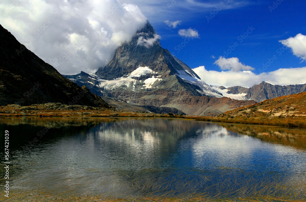 Landscape with a mountain Matterhorn view partially covered by clouds and reflected in the smooth surface of the lake, on a mountain Gornergrat, near Zermatt, in southern Switzerland