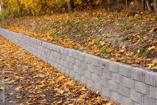 A retaining wall made of concrete elements protects the roadway and pavement from sliding down the slope. Autumn. photo