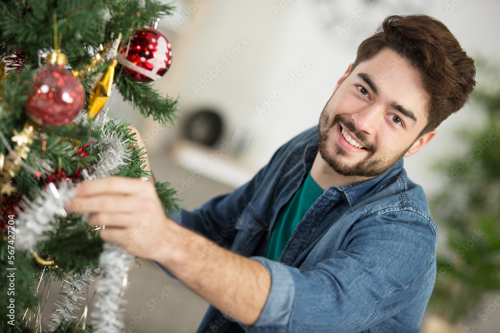 happy man opening present by christmas tree