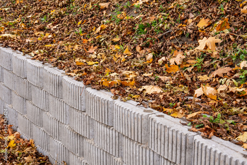 A retaining wall made of concrete elements protects the roadway and pavement from sliding down the slope. Autumn.