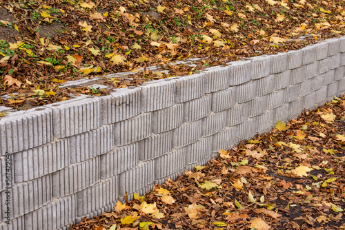 A retaining wall made of concrete elements protects the roadway and pavement from sliding down the slope. Autumn. © W Korczewski