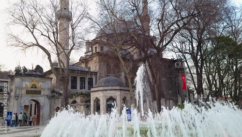  Exterior view of Eyup Sultan Camii in Istanbul. Arabic text translates  built on the grave site of Abu Ayyub al-Ansari. It is a complex building enclosed in walls. There is a pool with fountains photo