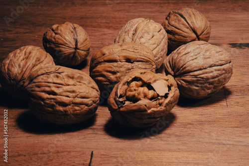 heaps of walnuts, one of which has been opened, waiting to be eaten on a wooden table	 photo