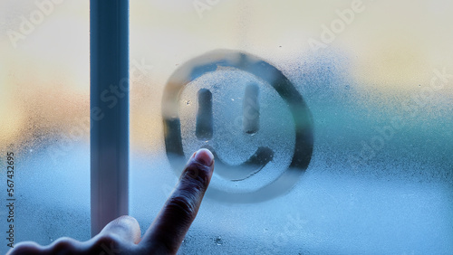 Persona dibujando una cara sonriente en la ventana un día de invierno photo
