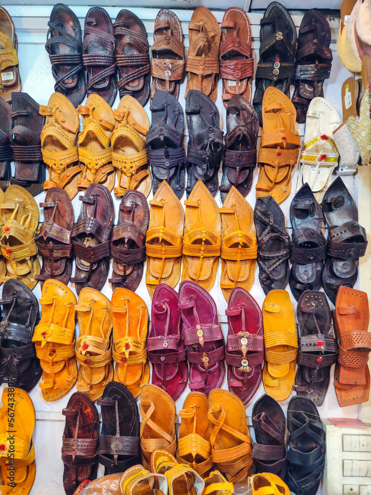 Stock photo of popular and traditional kolhapuri chappal display on wall for sale in the local shop.It is handmade leather chappal with unique design and color at Kolhapur, Maharashtra, India.