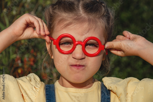 Portrait of capricious funny little girl in red fake glasses © ksenija1803z