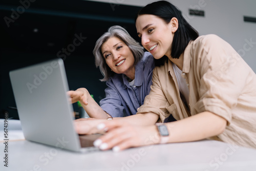 Smiling women browsing laptop together in office