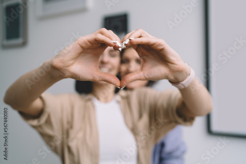 Crop woman showing heart gesture while standing with mother