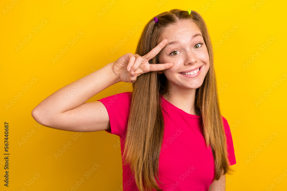 Photo portrait of youngster teenager girl wearing pink crop top show v-sign cover face friendly person smiling isolated on yellow color background Photo portrait of youngster teenager girl wearing pink crop top show v-sign cover face friendly person smiling isolated on yellow color background