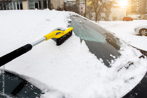 a brush for clearing the car from snow on the background of winter nature