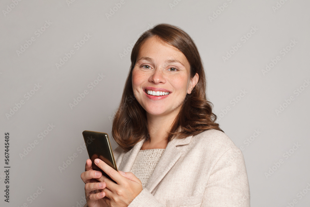 Photo of a positive emotional surprised young woman posing using mobile phone isolated over white studio wall background Photo of a positive emotional surprised young woman posing using mobile phone isolated over white studio wall background