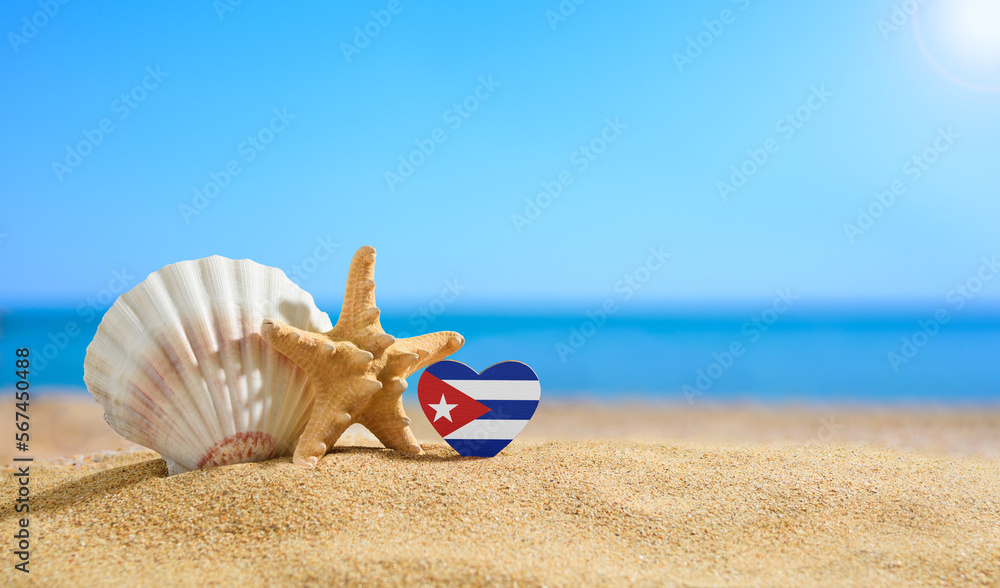 Obraz premium Beautiful beach in the Cuba. Flag of Cuba in the shape of a heart and shells on a sandy beach.