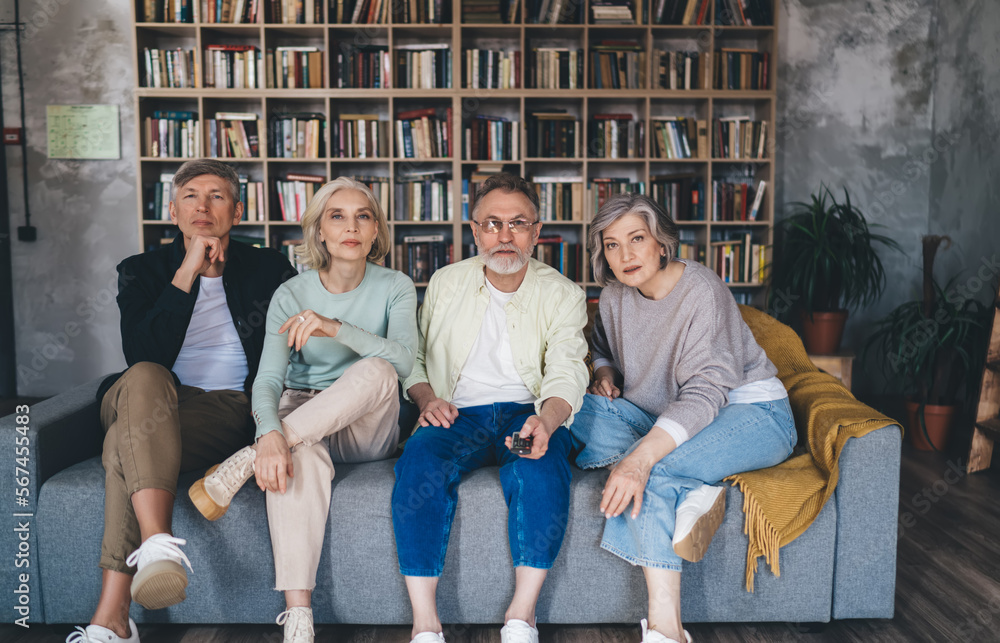 Group of pensive middle aged friends sitting on sofa