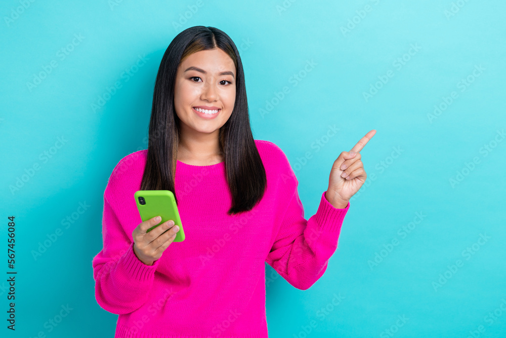 Photo of charming pretty korean young girl satisfied new samsung smartphone direct finger mockup eshop promo code isolated on cyan color background Photo of charming pretty korean young girl satisfied new samsung smartphone direct finger mockup eshop promo code isolated on cyan color background
