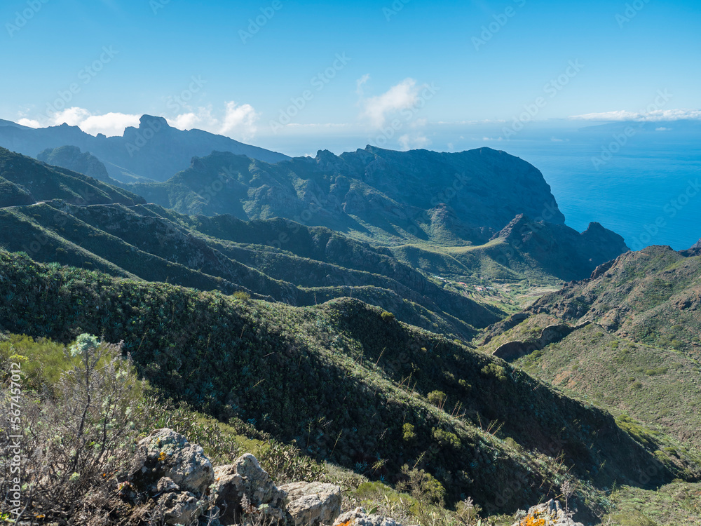 Dramatic lush green picturesque valley. Landscape with sharp rock formation, hills and cliffs seen from hiking trail at Park rural de teno, Tenerife, Canary Islands, Spain. sunny winter day, blue sky