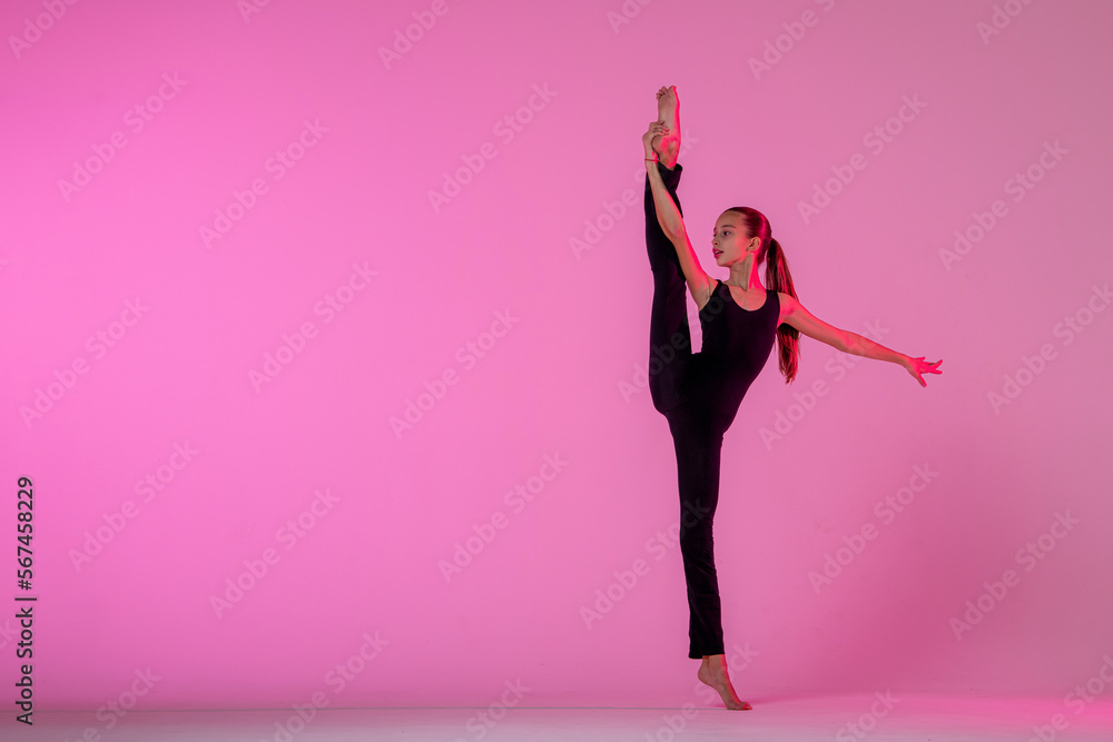 teenage girl in a tight black costume dancing a modern contemporary contemporary dancer isolated on a background in neon light.