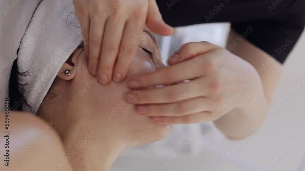 Therapist doctor making woman relaxing spa face cheek massage with hands. Smooth, healthy skincare treatment at salon. Detox and healing. Client in facial physical cosmetology session. Vertical shot Therapist doctor making woman relaxing spa face cheek massage with hands. Smooth, healthy skincare treatment at salon. Detox and healing. Client in facial physical cosmetology session. Vertical shot