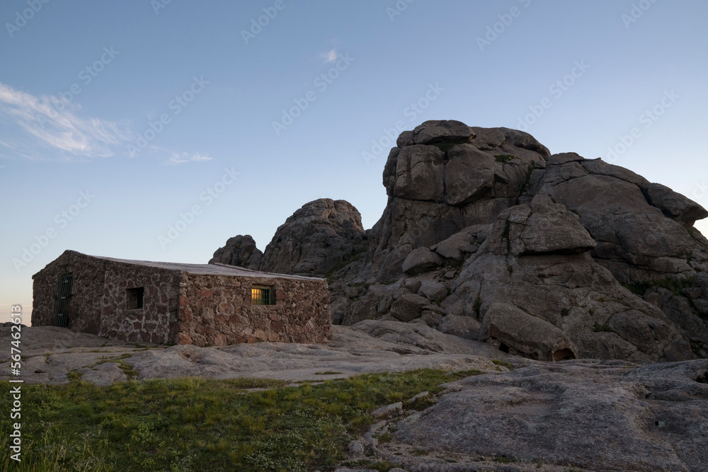 Refuge Nores in the top of The Giants rock massif in Cordoba, Argentina. View of the rocky hill, house and sky at nightfall. 