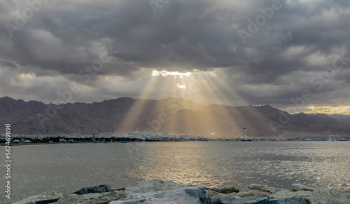 Sunrise with sunbeams through the clouds over Jordanian mountains range and A...
