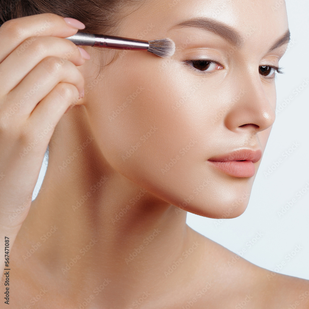 Young woman applies eye shadow with brush Young woman applies eye shadow with brush