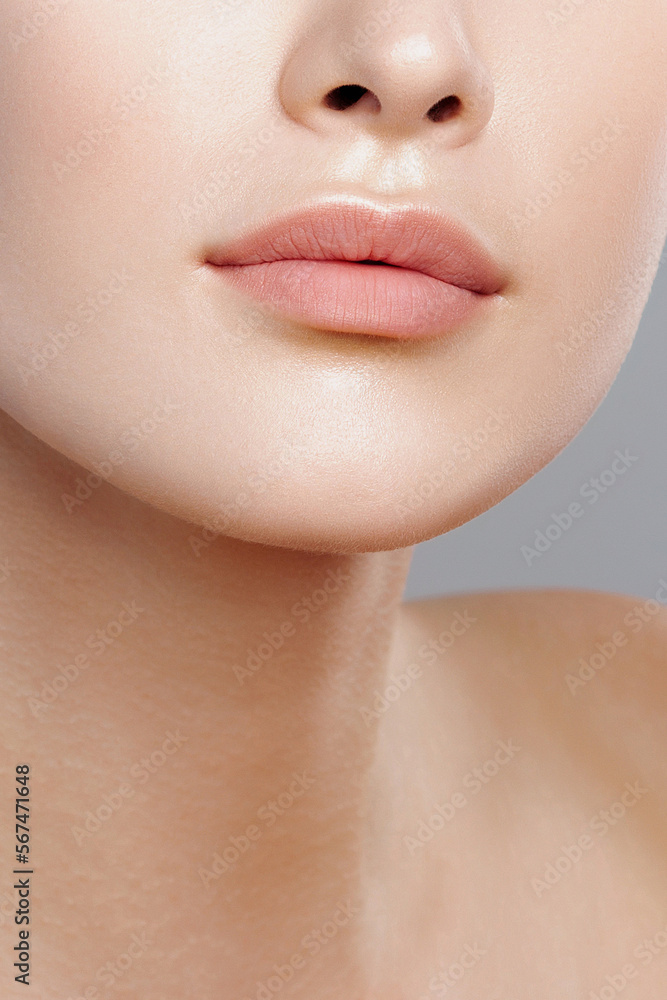 Lips of young beautiful woman closeup. Clean skin, nude makeup