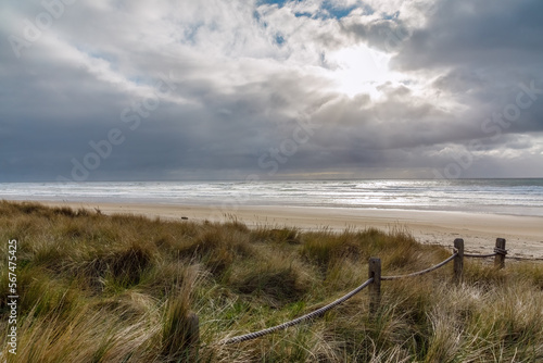 Sunbeams through the clouds over a beach and dunes with grass