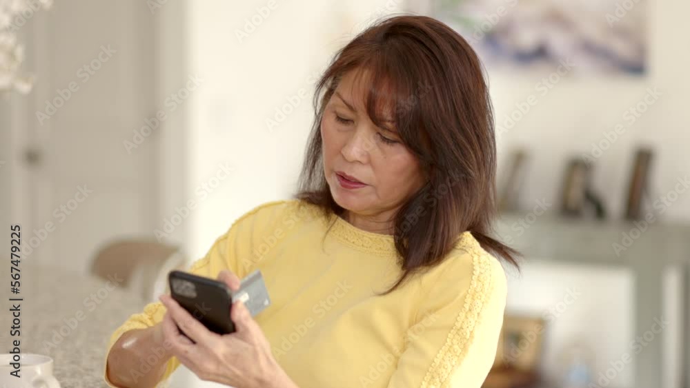 Smiling attractive mature woman relaxing shopping online with smartphone has success buying in leisure home living room Smiling attractive mature woman relaxing shopping online with smartphone has success buying in leisure home living room