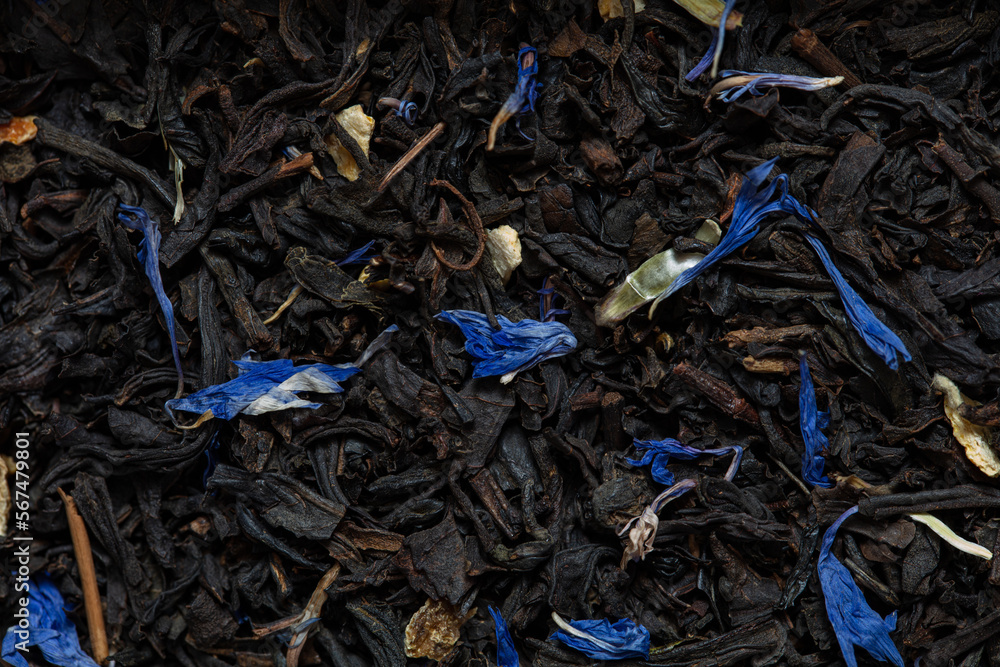 Closeup of black tea with orange, lemon peels and cornflower petals background Closeup of black tea with orange, lemon peels and cornflower petals background