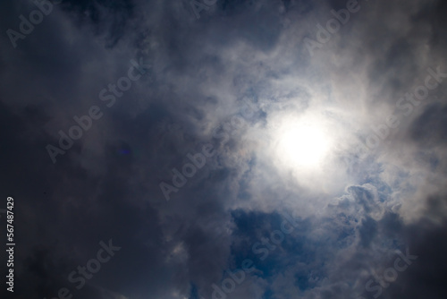 White cloud against stormy sky illuminated by the rays of the setting warm sun against a dark blue clear sky © vladimircaribb