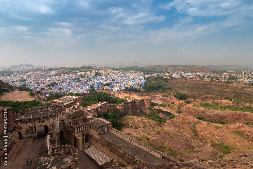 Top view of Mehrangarh fort with distant view of blue city Jodhpur, Rajasthan, India. Blue sky with white clouds in the background. Historical Fort is UNESCO world heritage site
