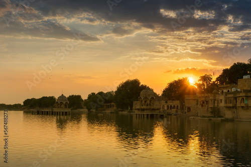 Beautiful sunset at Gadisar lake, Jaisalmer, Rajasthan, India. Setting sun and colorful clouds in the sky with view of the Gadisar lake. Connected with Indira Gandhi Canal for continuous water supply.