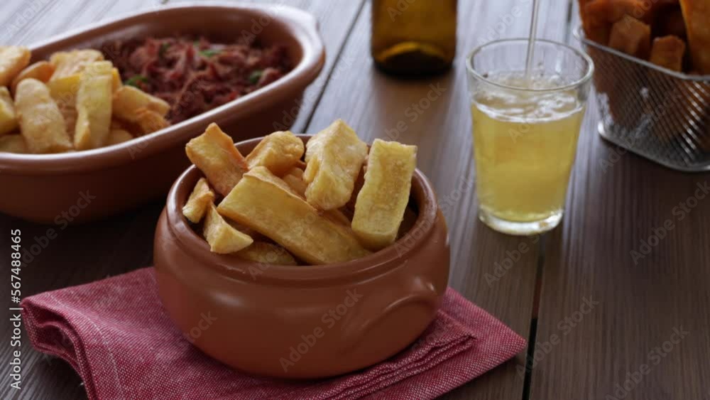 A portion of fried maniocs ( Mandiocas ) on a wooden table, traditional brazilian food. A portion of fried maniocs ( Mandiocas ) on a wooden table, traditional brazilian food.