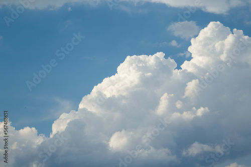 White cloud against stormy sky illuminated by the rays of the setting warm sun against dark blue clear sky