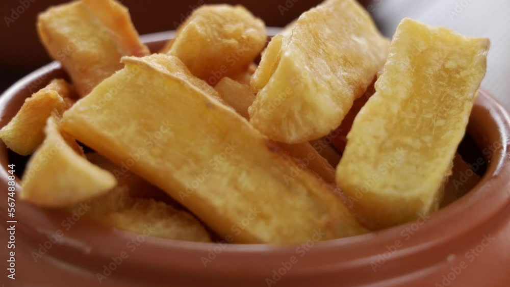 A portion of fried maniocs ( Mandiocas ) on a wooden table, traditional brazilian food. A portion of fried maniocs ( Mandiocas ) on a wooden table, traditional brazilian food.