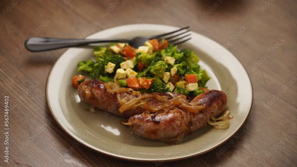 Crop person putting fork on plate with salad and sausages Crop person putting fork on plate with salad and sausages