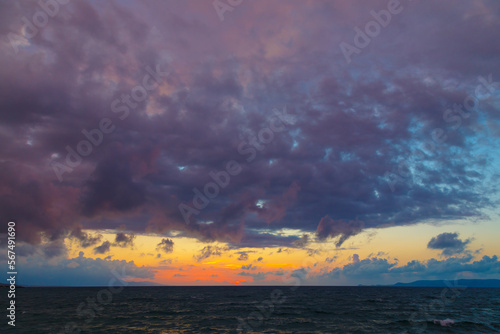Dark blue sea and purple clouds in setting sun have a rich color scheme. © vladimircaribb