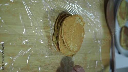 Vertical 4k video of woman storing homemade pancakes in transparent cellophane