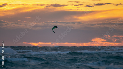 Person practicing kitesurfing in the sea, with a beautiful sunset in the background, in Castelldefels (Spain)