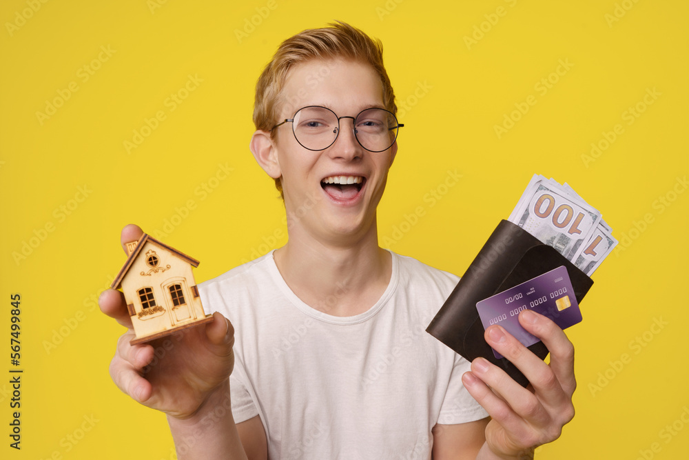Financing Home Purchase Concept. A happy young man holds in his hands a wallet with money and a credit card to buy his home. Financing Home Purchase Concept. A happy young man holds in his hands a wallet with money and a credit card to buy his home.