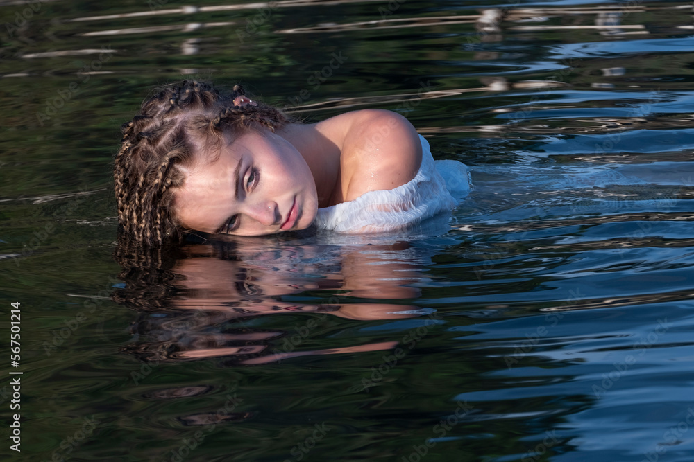 Giovane ragazza bionda con treccine riflessa nel lago