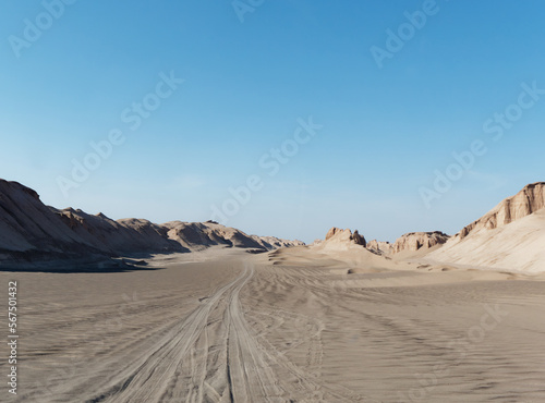 Low-angle view of the car trails in the sand and formations known as Kaluts in the background  Dasht-e Lut Desert  Iran 