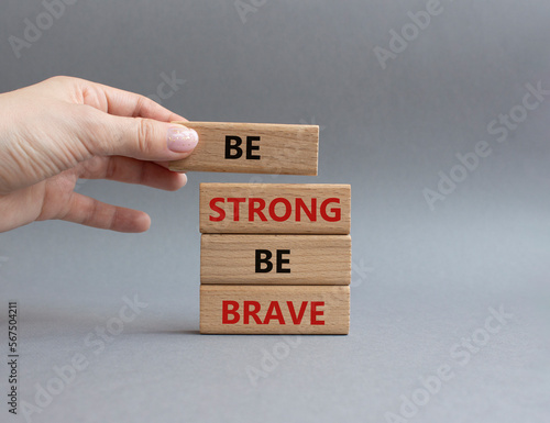 Be strong be brave symbol. Concept words Be strong be brave on wooden blocks. Beautiful grey background. Businessman hand. Business concept. Copy space.