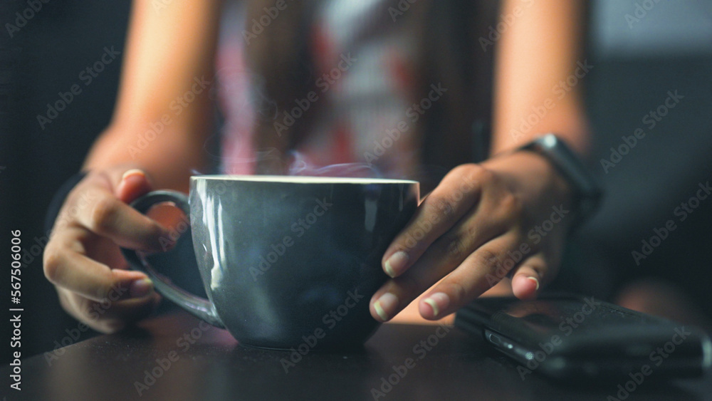 Hand close-up of unrecognizable young girl pick up cup of fresh hot tea, coffee, drink from table in morning sitting on sofa couch at home lifestyle. Happy cheerful woman relaxing, enjoying in summer Hand close-up of unrecognizable young girl pick up cup of fresh hot tea, coffee, drink from table in morning sitting on sofa couch at home lifestyle. Happy cheerful woman relaxing, enjoying in summer
