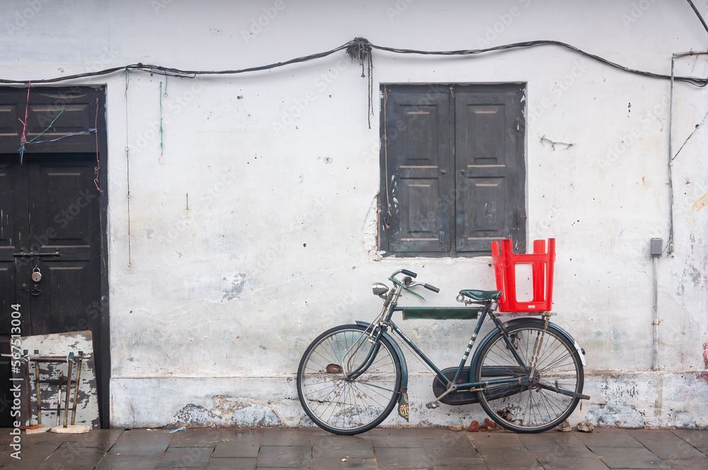 Parked bike near white wall with red chair